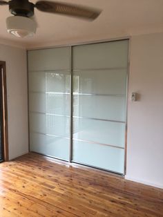 an empty room with sliding glass doors and hard wood flooring