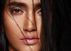 a close up of a woman's face with her hair blowing in the wind