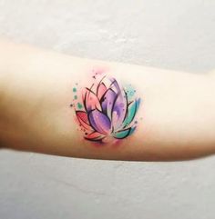 a watercolor lotus tattoo on the arm