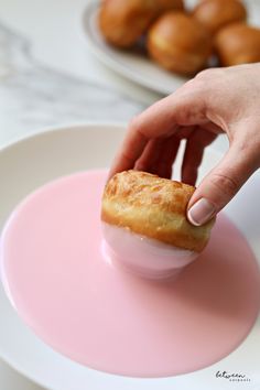 a person picking up a donut from a pink plate