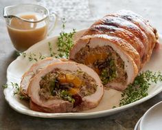 a white plate topped with meat covered in toppings next to a cup of coffee