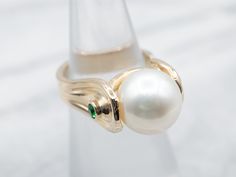 This gorgeous modernist piece is crafted of polished yellow gold that is polished to a perfect shine. Utterly sleek, this vintage piece features a single, luscious pearl accented by sparkling diopside gemstones!Metal: 14K Yellow GoldGem: PearlGem Measurements: 10.5 mm, RoundAccents: 2 Diopside totaling .08 CaratsRing Size: 4.25Marks: "14K" Stamped on the inside band Elegant Green Pearl Ring With Gemstone, Elegant Green Gemstone Pearl Ring, Fine Jewelry Gold Pearl Ring With Polished Finish, Elegant 14k Gold Pearl Ring With Polished Finish, Gold Pearl Ring With Polished Finish, 14k Gold Pearl Ring With Polished Finish, 14k Yellow Gold Polished Pearl Ring, Gold Pearl Ring, Pocket Watch Chain