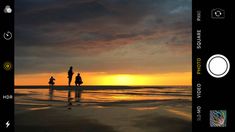 two people walking on the beach at sunset