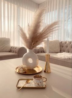 a white table topped with a vase filled with feathers next to a mirror and candle holder