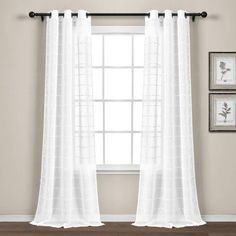 a white curtain hanging on the side of a window in front of a wooden floor