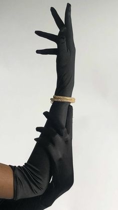 a woman wearing black gloves and a gold bracelet