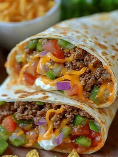 a burrito cut in half and topped with cheese, onions, peppers, and ground beef