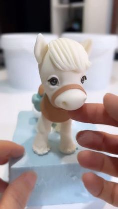 a small toy horse is being held by someone's hand in front of the camera