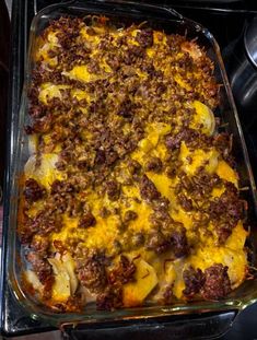 a casserole dish with meat, cheese and potatoes in it on the stove