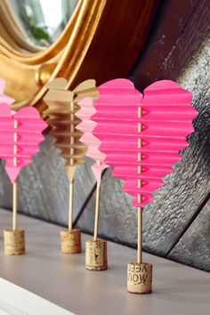 pink heart shaped paper lanterns are lined up on a shelf