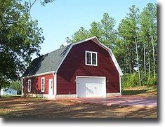 a red barn with a white door and windows on the front is surrounded by trees