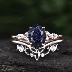 an oval shaped blue diamond surrounded by white diamonds on top of a wooden table with green leaves