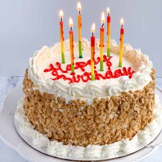 a birthday cake with white frosting and lit candles on top, sitting on a plate