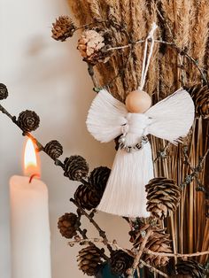 a white angel ornament sitting on top of a table next to a lit candle