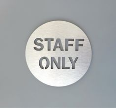 a stainless steel sign that says staff only on the side of a gray wall,