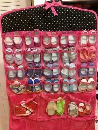 a pink wall hanging filled with lots of baby shoes