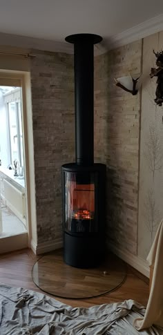 a wood burning stove in the corner of a room next to a bed with sheets on it