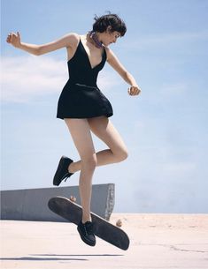 a woman in a short black dress is doing a trick on a skateboard