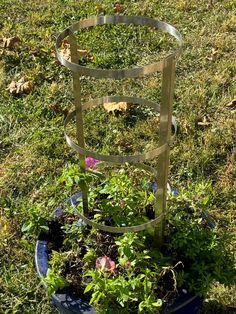 a metal planter filled with plants on top of a grass covered field next to a tree