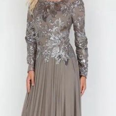 a woman wearing a long dress with silver sequins on the shoulders and sleeves