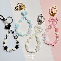 three different key chains with charms attached to them on a white and pink background,