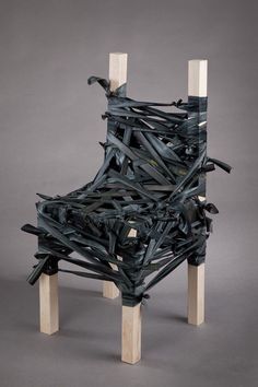 a chair made out of wooden sticks and pieces of black paint on top of it