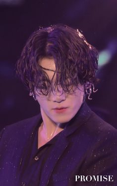 a man with curly hair wearing a purple suit