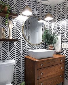 a white toilet sitting next to a wooden dresser under a mirror on top of a wall