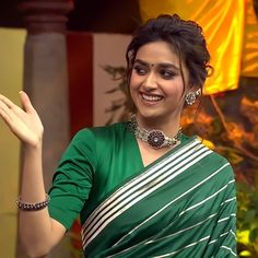 a woman in a green and white sari holding her hand up to the side