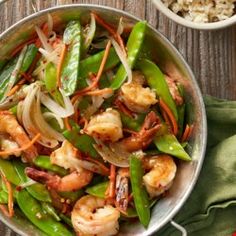 a bowl filled with shrimp and green beans next to some other dishes on a table