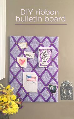 a bulletin board with pictures and magnets on it next to a vase filled with flowers