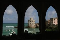 the view from inside an arched window looking out at boats in the water and old buildings