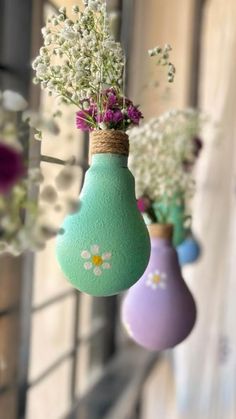 three vases with flowers hanging from them