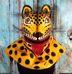 a leopard mask with black and yellow spots on it's face, sitting against a wooden wall