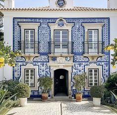 a large blue and white building with potted plants in front of the entrance to it