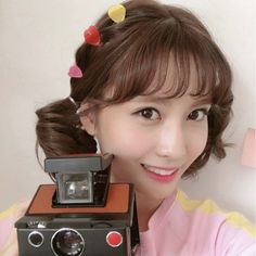 a woman holding up an old camera with hearts on her head and smiling at the camera