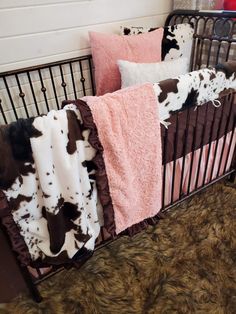 a baby crib with pink, brown and white blankets