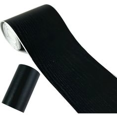 a black tie laying on top of a white surface next to a roll of tape