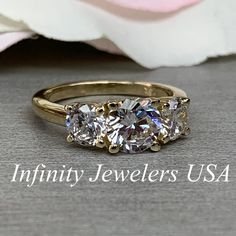 three stone diamond ring with the words infinity jewelers usa written below it