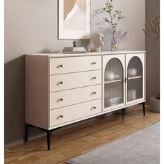 a white cabinet with glass doors and drawers in a room next to a rug on the floor