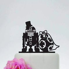 a cake topper with a robot and dog on it next to a pink flower