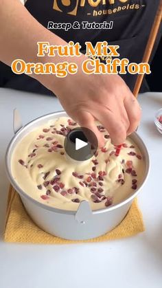 a person is dipping some fruit into a bowl with orange chiffon in it