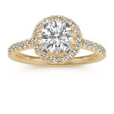 a yellow gold engagement ring with diamonds on the band and a round center stone in the middle