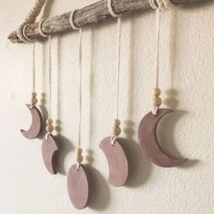 the moon and crescents are hanging on the wall next to a branch with some wood beads