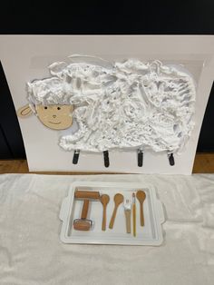 there is a tray with utensils in it and a sheep cut out on the wall