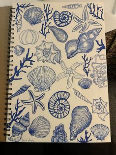 a notebook with blue ink drawings of shells and corals