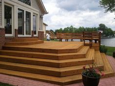 a wooden deck next to a lake with benches