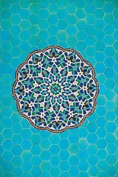 a blue and green tile with an intricate design in the center on it's surface