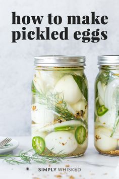 two mason jars filled with pickled eggs and herbs