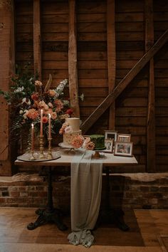 a table with flowers and candles on it in front of a wooden wall next to stairs